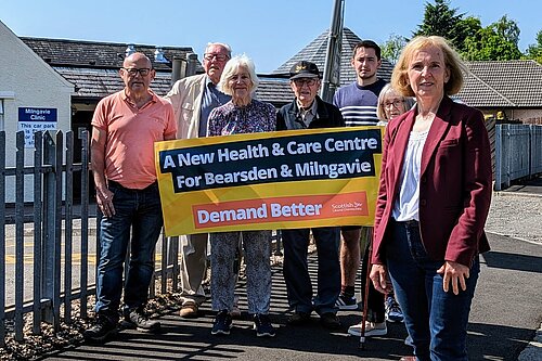 Susan Murray in front of campaigners holding up a banner calling for a new health and care centre for Milngavie and Bearsden