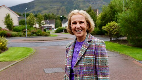 Susan Murray smiling in a purple and green tartan jacket.