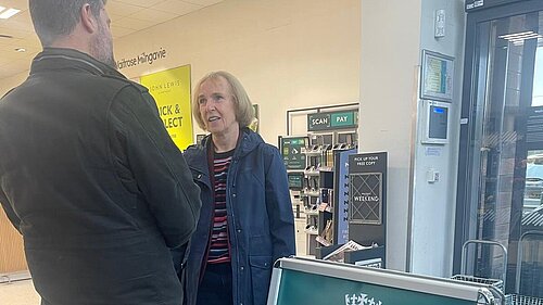 Susan Murray talking with a resident next to an A board with the words Susan Murray MP Advice Surgery.