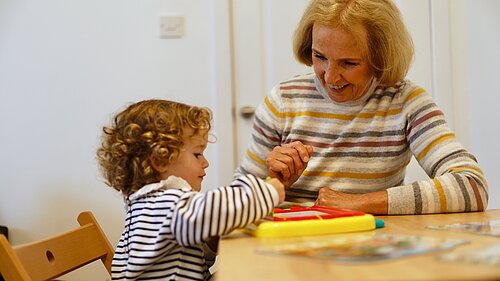 Susan Murray sitting at a table with a child playing a game.