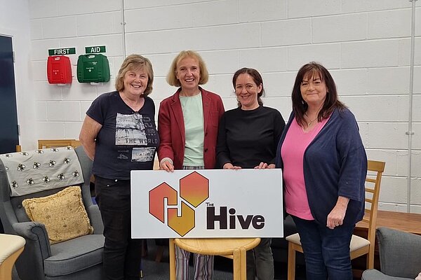 Susan Murray MP with three volunteers standing behind a sign reading "The Hive"