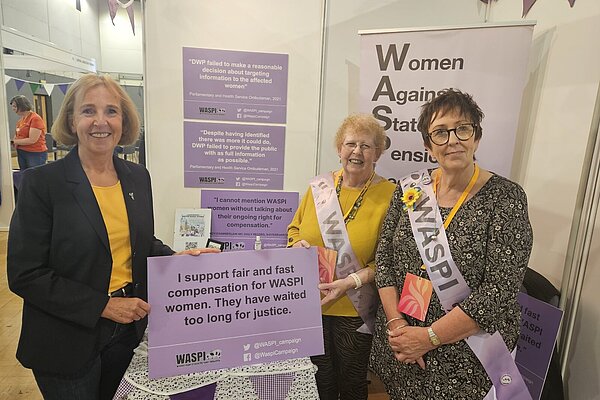 Susan Murray MP at a WASPI stall with two campaigners holding up a pledge to support fair and fast compensation.