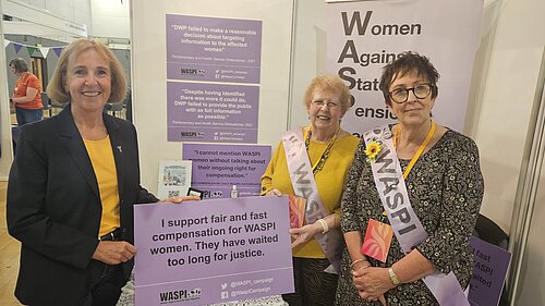 Susan Murray MP at a WASPI stall with two campaigners holding up a pledge to support fair and fast compensation.