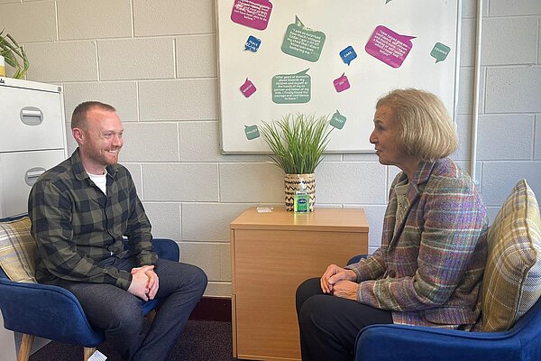 Susan Murray MP sitting in a chair across from a man from EDAMH sitting in a chair.