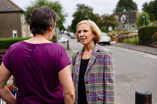 Susan Murray talking with a resident on a street.