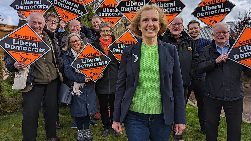 Susan Murray in front of Scottish Liberal Democrat activists holding orange diamonds