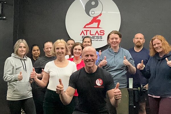 Susan Murray with members all smiling with their thumbs up at Atlas Fitness.