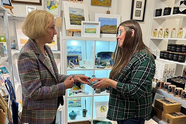 Susan Murray, MP for Mid Dunbartonshire, discussing with a lady about a coloured piece of pottery that they are both holding.