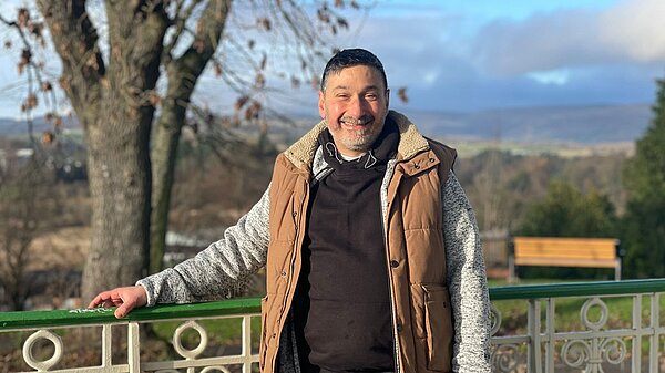 Marthos Christoforou standing next to a park fence leaning on it