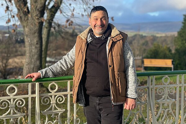 Marthos Christoforou standing next to a park fence leaning on it